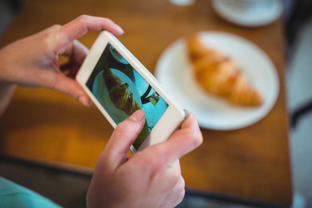 Person taking a picture of food for instagram using their phone - Tips on how to take attractive Instagram photos - Image