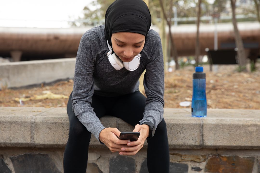 Woman in hijab using smartphone outdoors - Free Images, Stock Photos and Pictures on Pikwizard.com