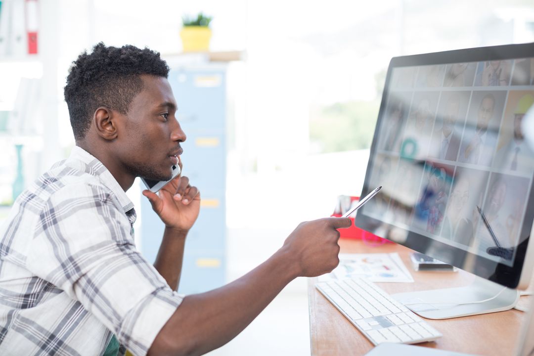 Male worker pointing his pen at the computer screen while answering a call - Simple but powerful tactics for crafting compelling ad copies that drive sales - Image