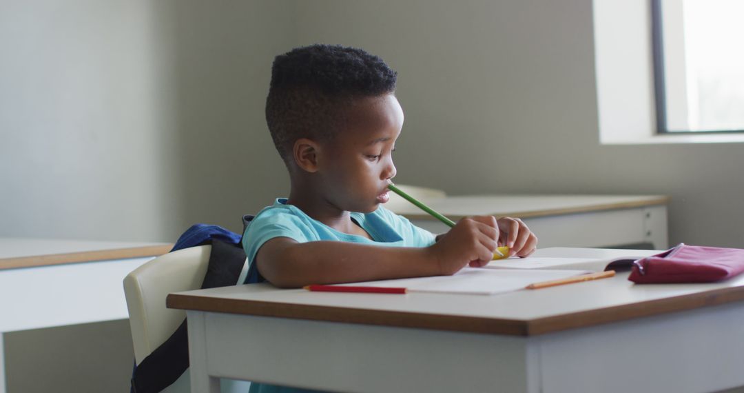 Image of african american boy sitting at desk during lesson in classroom - Free Images, Stock Photos and Pictures on Pikwizard.com