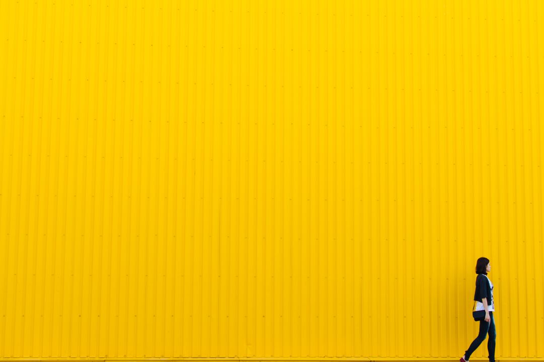 Large yellow wall with woman walking in front