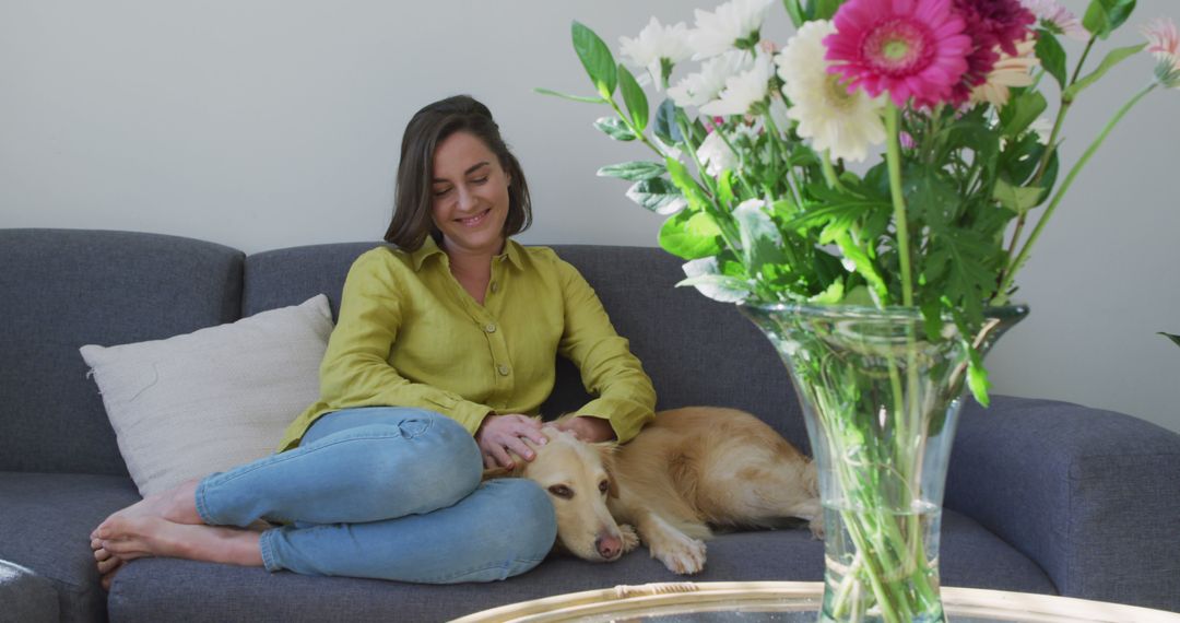 Caucasian woman smiling and sitting on couch with dog - Free Images, Stock Photos and Pictures on Pikwizard.com