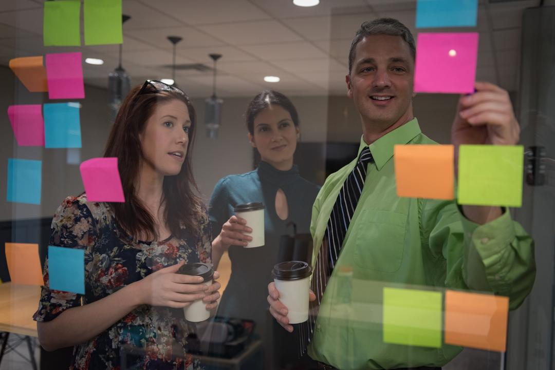 Image of Business Colleagues Discussing Over Sticky Notes Seen Through Glass