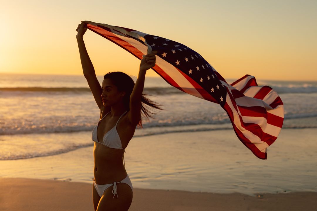 Woman standing with waving American flag on the beach - Free Images, Stock Photos and Pictures on Pikwizard.com