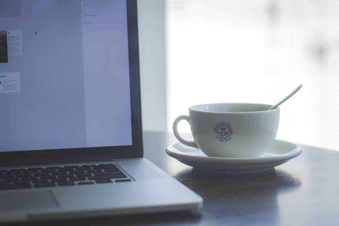 Close up image of the side of a laptop and a coffee cup - Simple but powerful tactics for crafting compelling ad copies that drive sales - Image