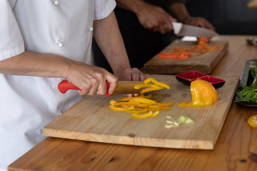 Image of a Cook Cutting Peppers on a Chopping Board