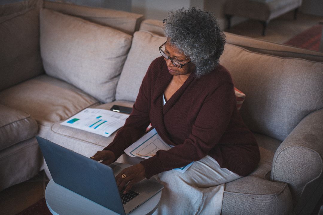 Woman wearing glasses typing on her laptop on her couch at night - Expert online marketing tips to improve your digital strategy and make more money - Image