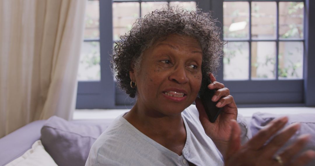 Senior african american woman sitting on sofa and talking on smartphone - Free Images, Stock Photos and Pictures on Pikwizard.com