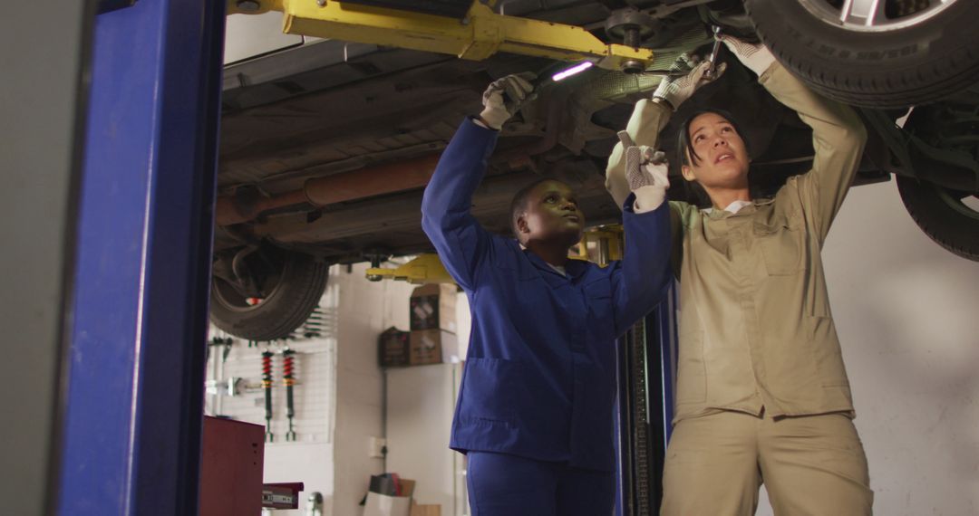 Image of two diverse female car mechanics changing tyre - Free Images, Stock Photos and Pictures on Pikwizard.com