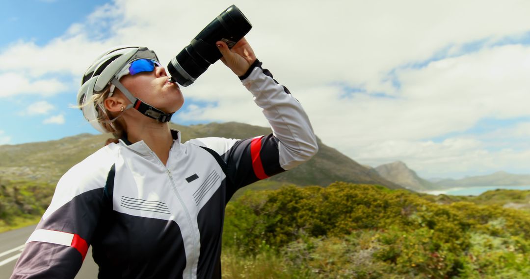 Caucasian female cyclist in helmet and sunglasses drinking water