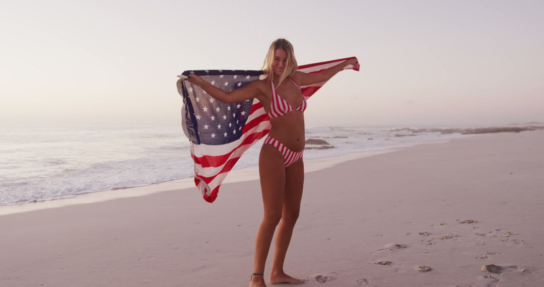 Portrait of happy caucasian woman holding flag of usa and smiling on beach - Free Images, Stock Photos and Pictures on Pikwizard.com