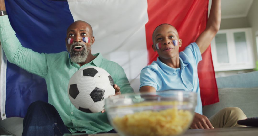 Image of happy african american father and son with soccer ball watching match - Free Images, Stock Photos and Pictures on Pikwizard.com