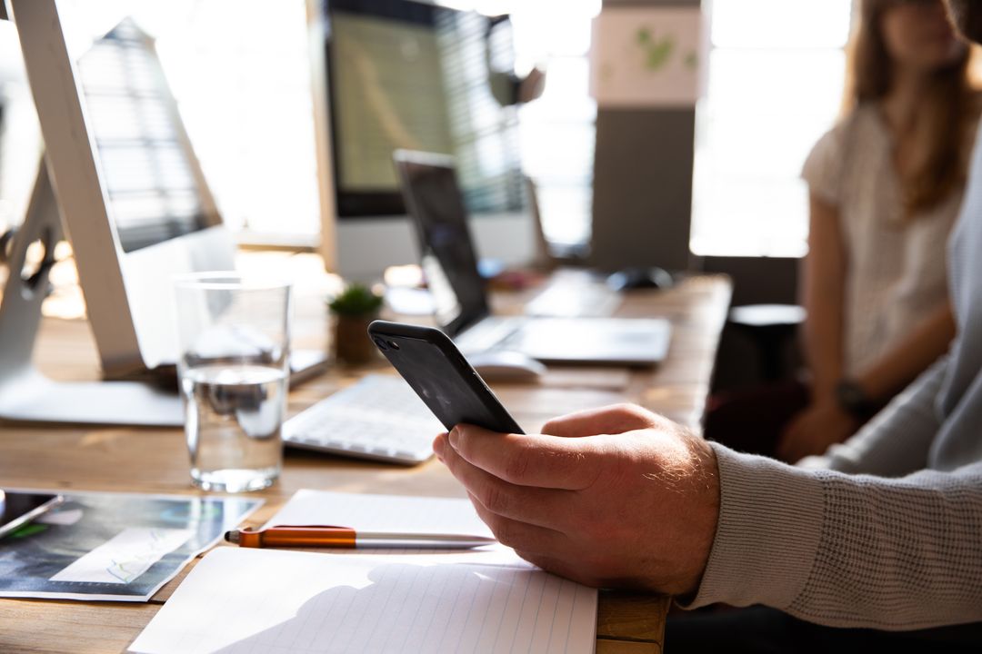 Close up image of a business worker on their phone at a shared desk