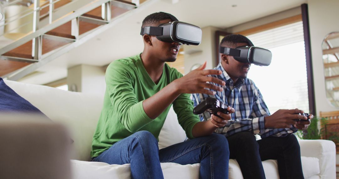 African american teenage twin brothers sitting on couch using vr headsets and playing computer game - Free Images, Stock Photos and Pictures on Pikwizard.com
