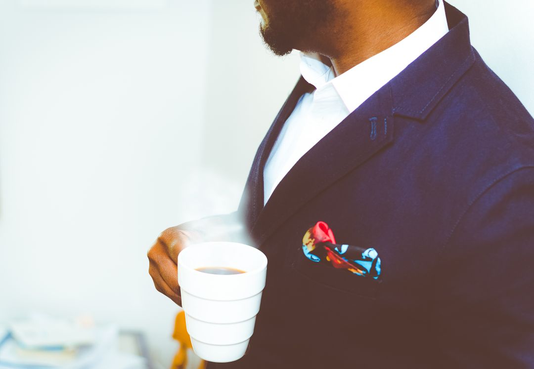 Man in fashionable blue suit holding a cup of coffee