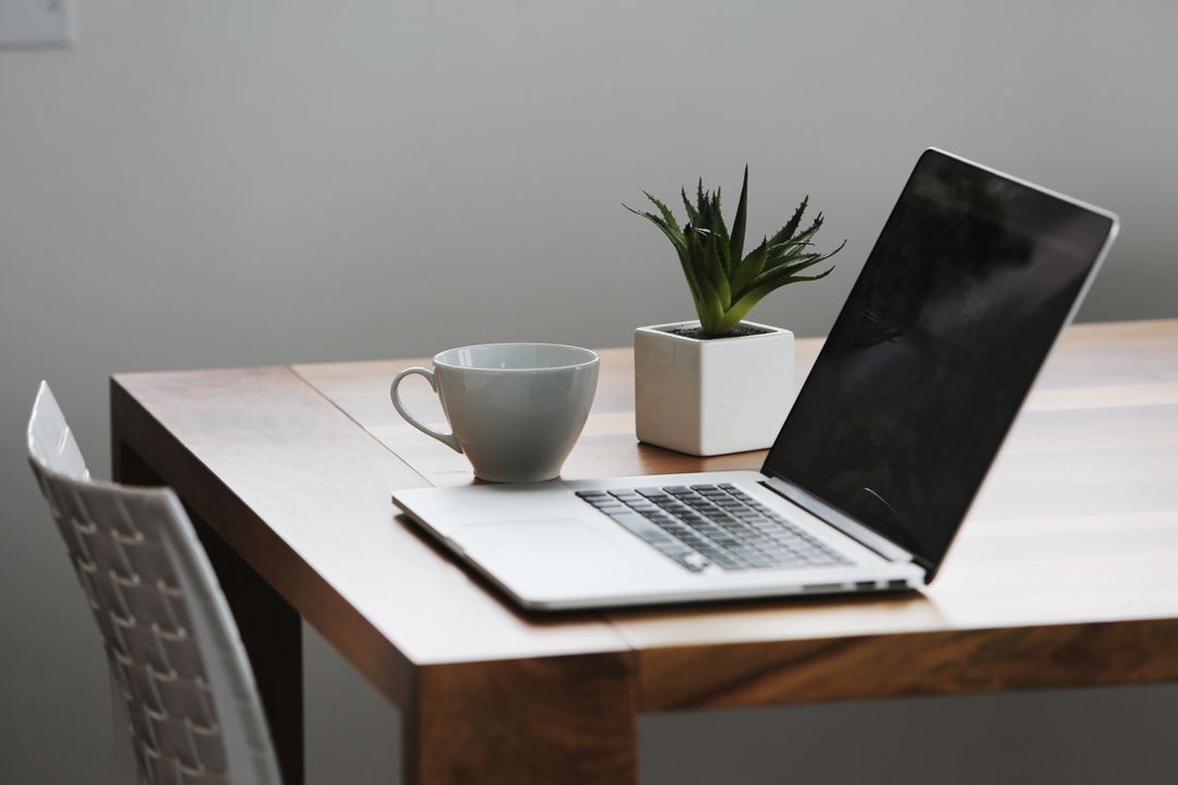 Image of a laptop open on a wooden desk with a coffee cup and green plant - Simple but powerful tactics for crafting compelling ad copies that drive sales - Image