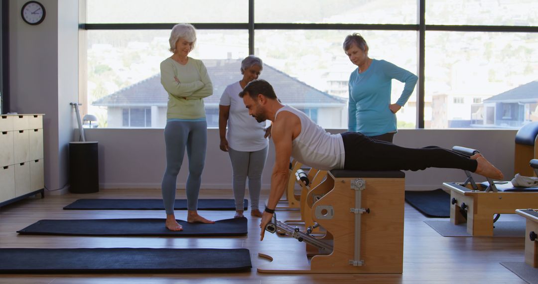 Senior women attentively learn Pilates from a young instructor