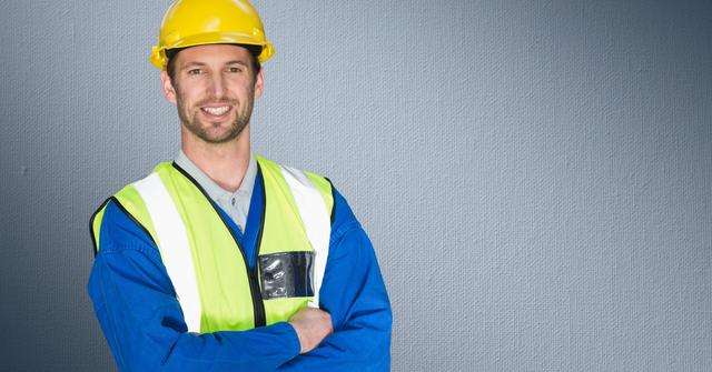 Construction worker standing with his arms crossed against grey background - Download Free Stock Photos Pikwizard.com