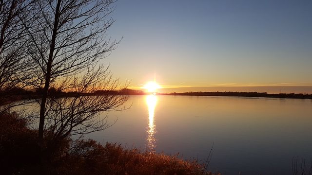 the sun setting over a lake - Download Free Stock Photos Pikwizard.com