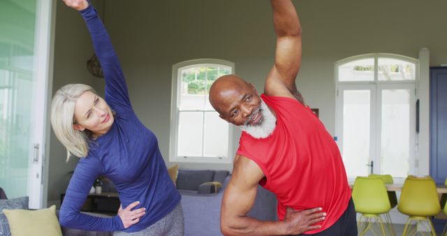 Mixed race senior couple performing stretching exercise together at home. retirement and active senior lifestyle concept