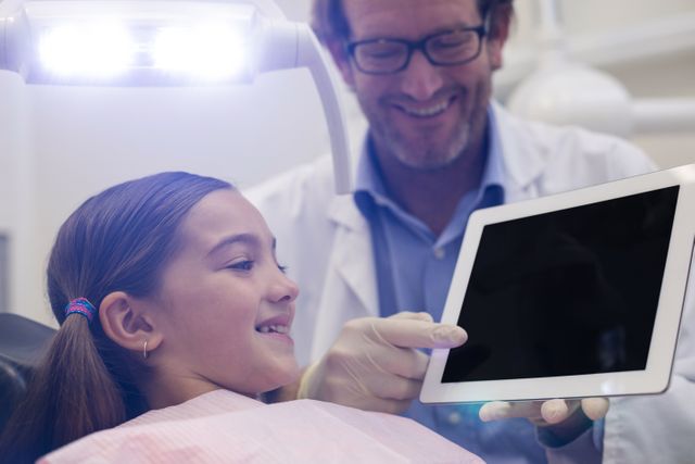 Dentist showing digital tablet to young patient - Download Free Stock Photos Pikwizard.com