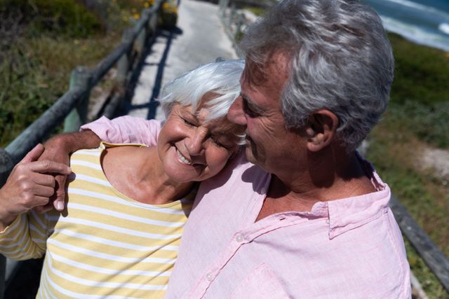 Senior caucasian couple hugging embracing each other on bridge near the beach - Download Free Stock Photos Pikwizard.com
