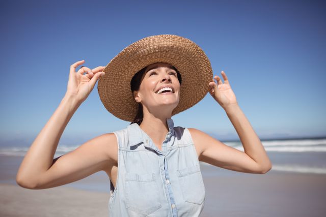 Happy woman wearing sun hat at beach - Download Free Stock Photos Pikwizard.com