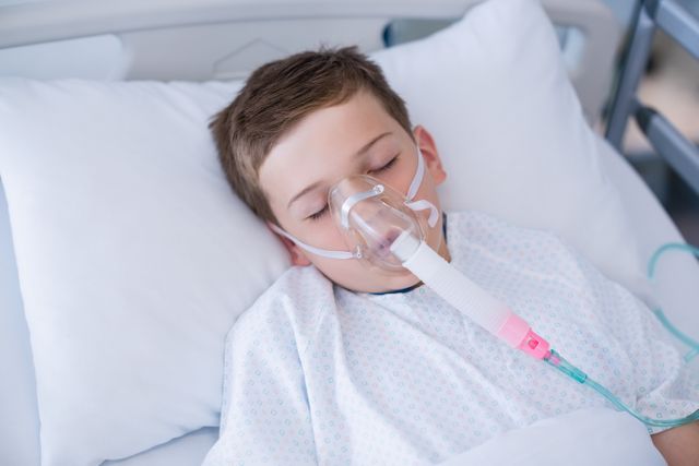 Boy patient wearing oxygen mask lying on hospital bed - Download Free Stock Photos Pikwizard.com