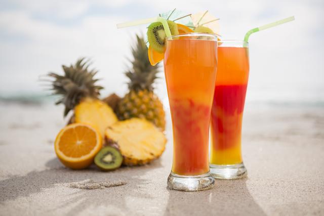 Two glasses of cocktail drink and tropical fruits kept on sand - Download Free Stock Photos Pikwizard.com