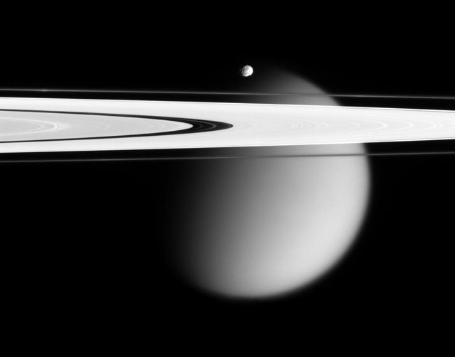 The Cassini spacecraft delivers this stunning vista showing small,  battered Epimetheus and smog-enshrouded Titan, with Saturn A and F  rings stretching across the scene