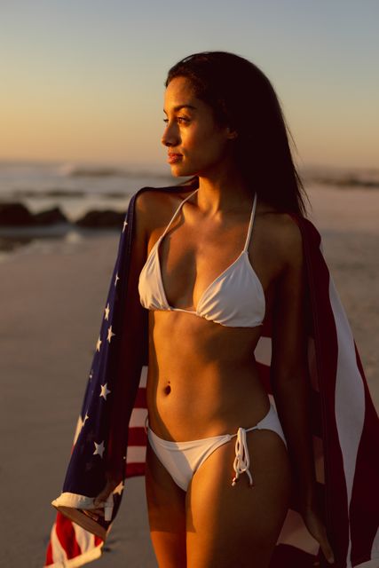 Woman with an American flag standing on the beach - Download Free Stock Photos Pikwizard.com