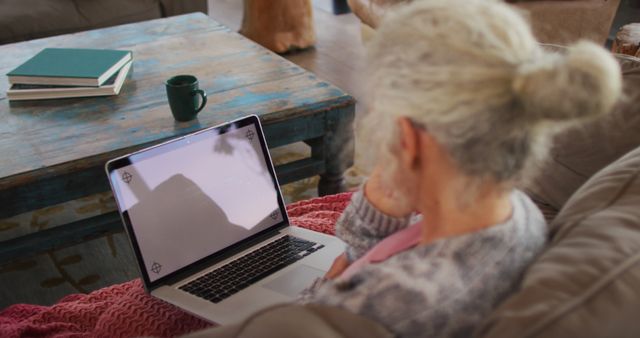 Senior mixed race woman sitting on sofa using laptop. retirement and senior lifestyle, spending time alone at home.