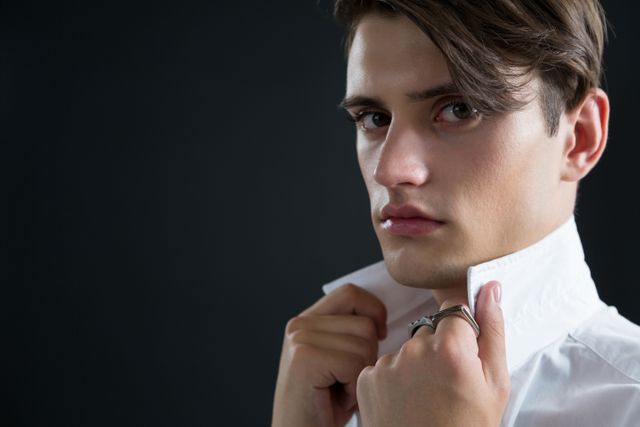 Androgynous man holding his collar against black background - Download Free Stock Photos Pikwizard.com