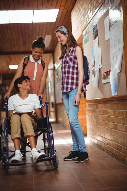 Schoolgirls talking with her disabled friend in corridor - Download Free Stock Photos Pikwizard.com