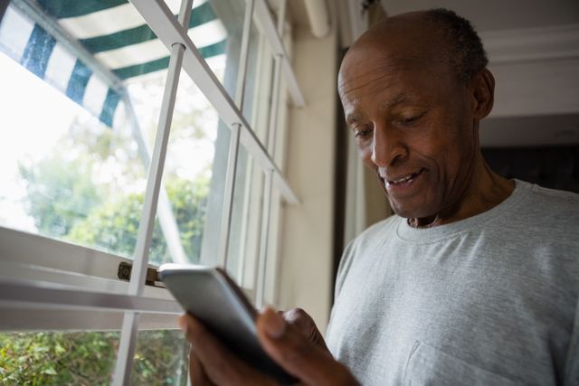 Senior man using mobile phone by window - Download Free Stock Photos Pikwizard.com