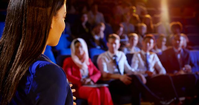 Rear view of young mixed race businesswoman speaking in business seminar at auditorium. Audience listening her 4k