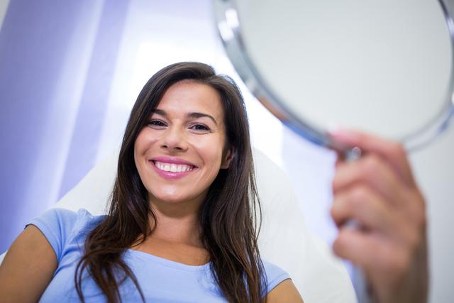 Smiling patient holding a mirror at clinic - Download Free Stock Photos Pikwizard.com