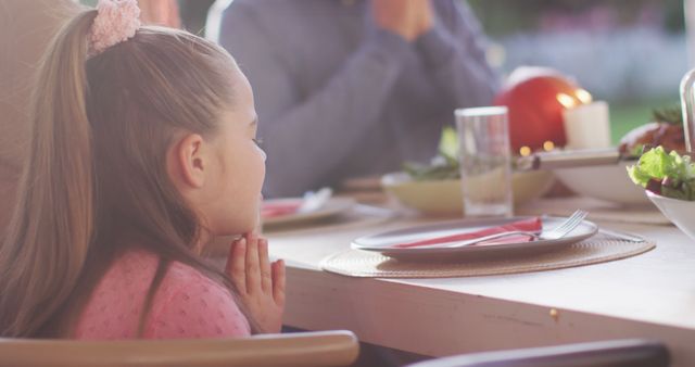 Image of happy caucasian daughter saying grace at table before family meal. Family, domestic life and togetherness concept digitally generated image.