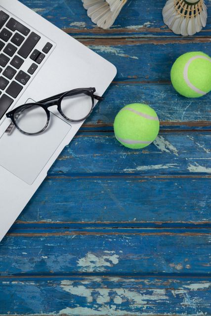 Overhead view of laptop and eyeglasses with shuttlecocks by tennis balls - Download Free Stock Photos Pikwizard.com