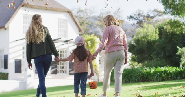 Image of happy caucasian mother and daughter walking with grandmother to trick or treat at halloween. Family, domestic life and togetherness concept digitally generated image.