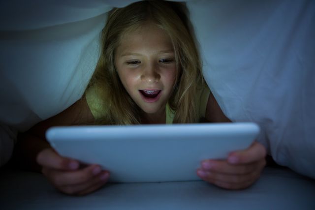 Happy girl using tablet computer with blanket on head - Download Free Stock Photos Pikwizard.com
