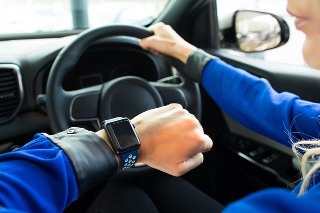 Cropped image of woman looking at smart watch during test drive - Download Free Stock Photos Pikwizard.com
