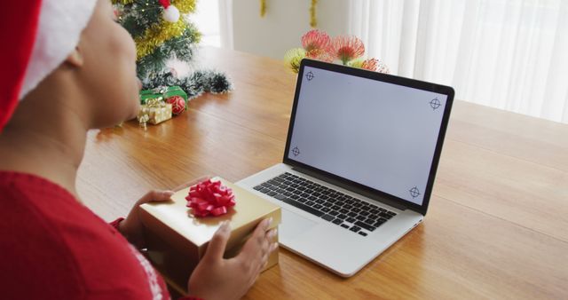 Happy african american plus size woman in santa hat, making image call using laptop at christmas. christmas, winter, tradition and celebration at home.