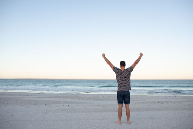 Man standing with arms outstretched on the beach  - Download Free Stock Photos Pikwizard.com