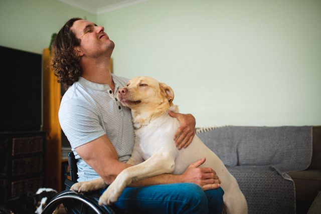 Caucasian disabled man sitting on the wheelchair hugging his dog at home - Download Free Stock Photos Pikwizard.com