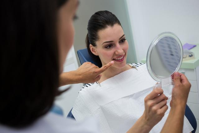 Dentist showing mirror to female patient - Download Free Stock Photos Pikwizard.com