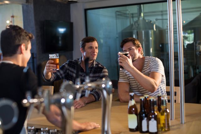 Friends enjoying beer at bar - Download Free Stock Photos Pikwizard.com