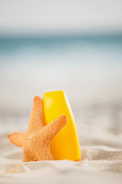 Bottle of sunscreen lotion and starfish kept on sand at beach