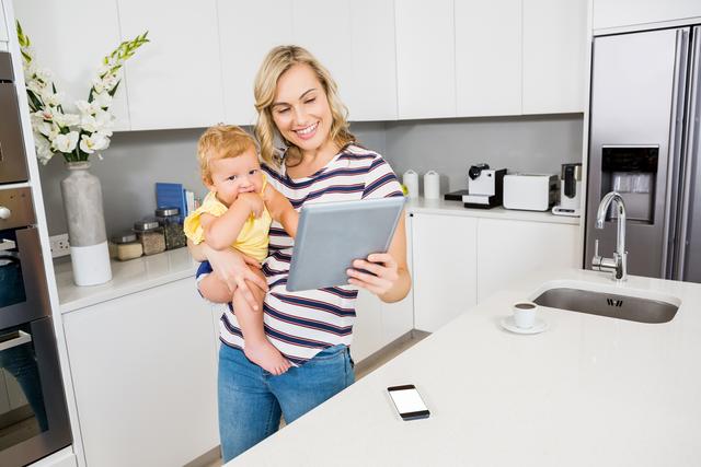 Mother and baby girl using digital tablet in kitchen - Download Free Stock Photos Pikwizard.com