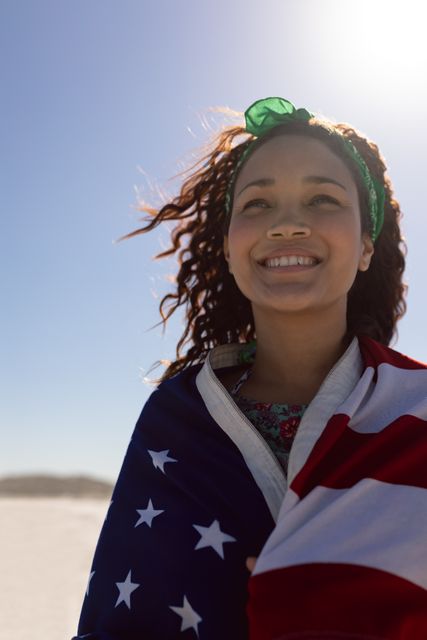 Beautiful young woman wrapped in american flag on beach in the sunshine - Download Free Stock Photos Pikwizard.com